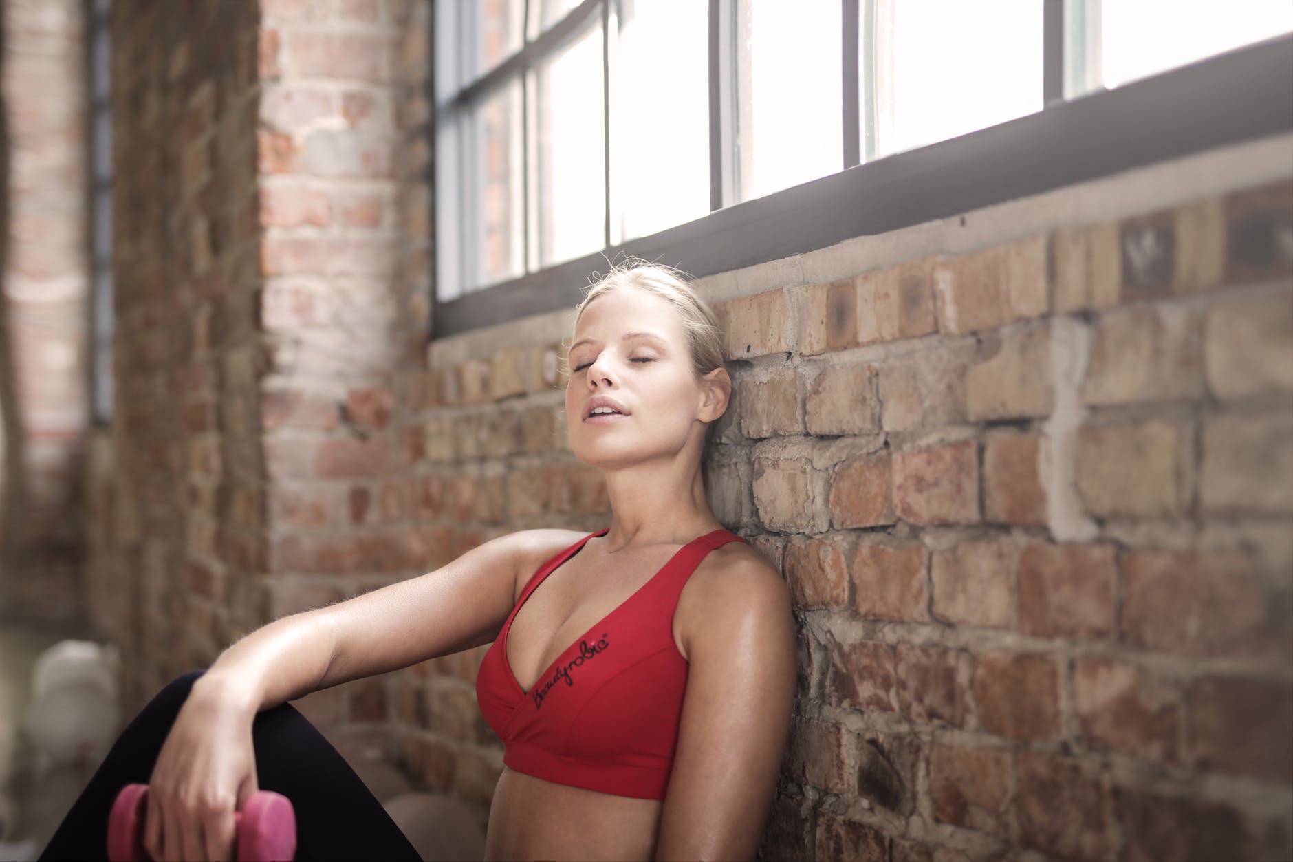 You Notice Shortness of Breath woman in red brassier leaning on brown brick wall